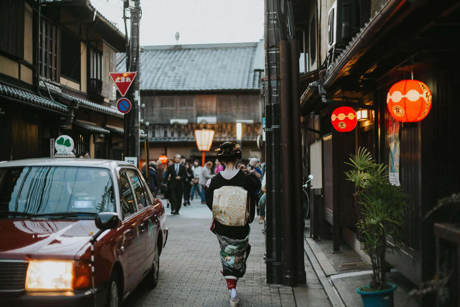 艺伎行走在京都祇园的石板街巷中，街灯初上