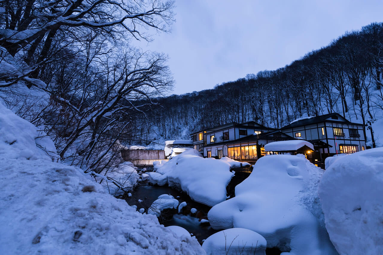 藏王温泉乡夜景,被雪覆的传统旅馆与溪流交织